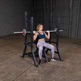 Woman performing shoulder press on PCL Oly Shoulder Press Bench with weights and sturdy steel frame.